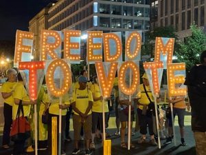 Picture of members of the Reeb Voting Rights Project holding individual letter signs that spell Freedom To Vote at a nighttime protest
